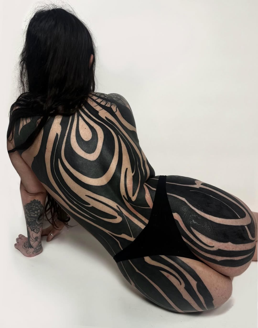 Large-scale flowing blackwork across the back and legs by Dhen